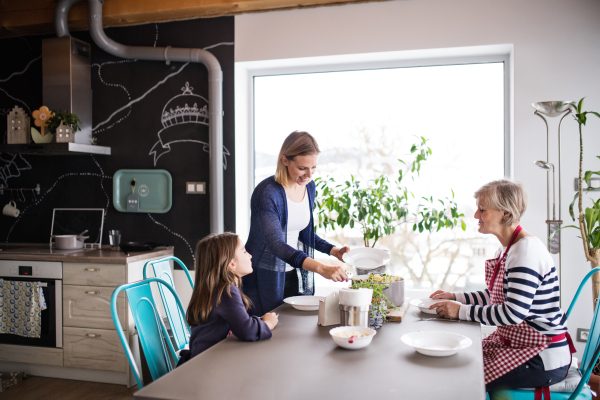 A small girl with her mother and grandmother at home, eating. Family and generations concept.