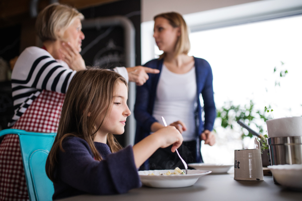 A small girl with her mother and grandmother at home, eating. Family and generations concept.