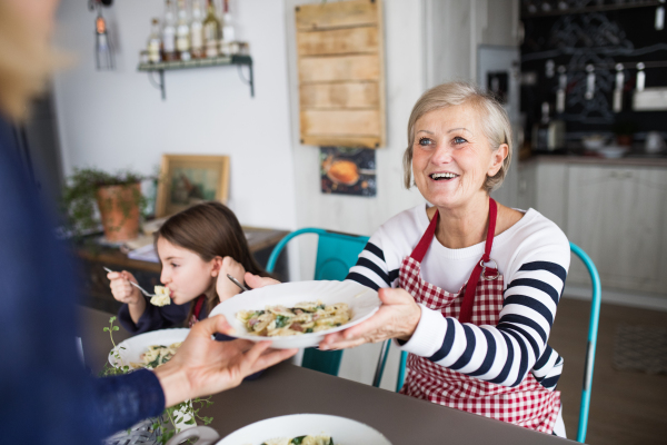 A small girl with her mother and grandmother at home, eating. Family and generations concept.