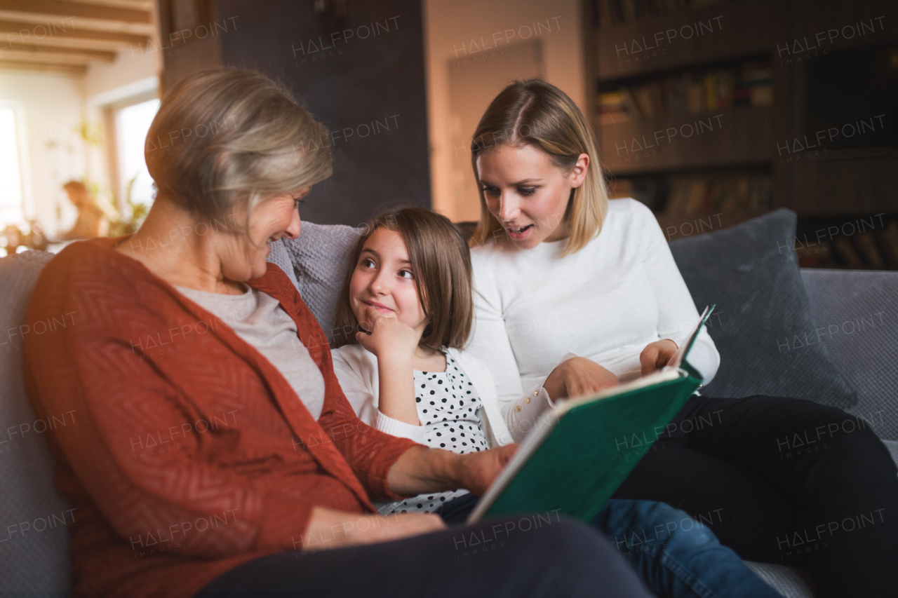 A small girl with her mother and grandmother at home. Family and generations concept.