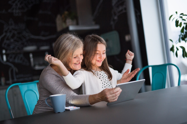 A small girl and her grandmother with tablet at home. Family and generations concept.