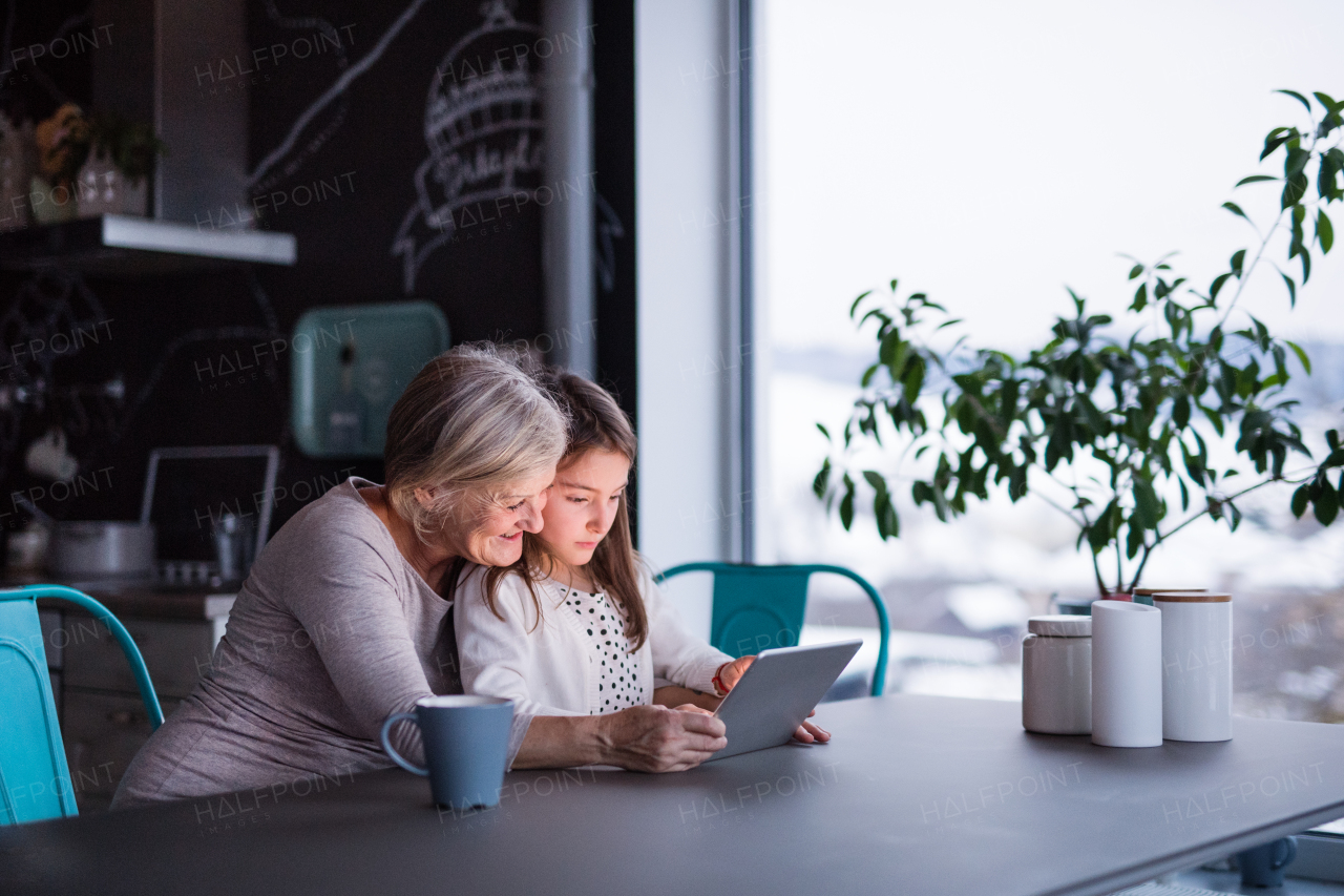 A small girl and her grandmother with tablet at home. Family and generations concept.