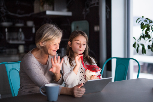 A small girl and her grandmother with tablet at home. Family and generations concept.