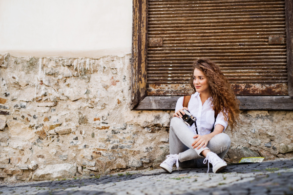 Beautiful young tourist with camera and backpack in the old town.