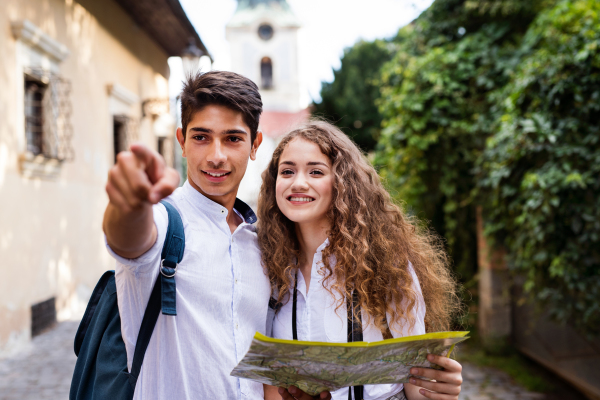 Two beautiful young tourists with map and camera in the old town. The boy pointing his finger.