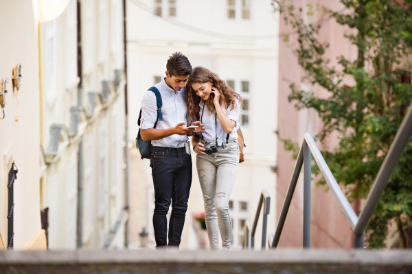 Two beautiful young tourists with smartphone and camera in the old town