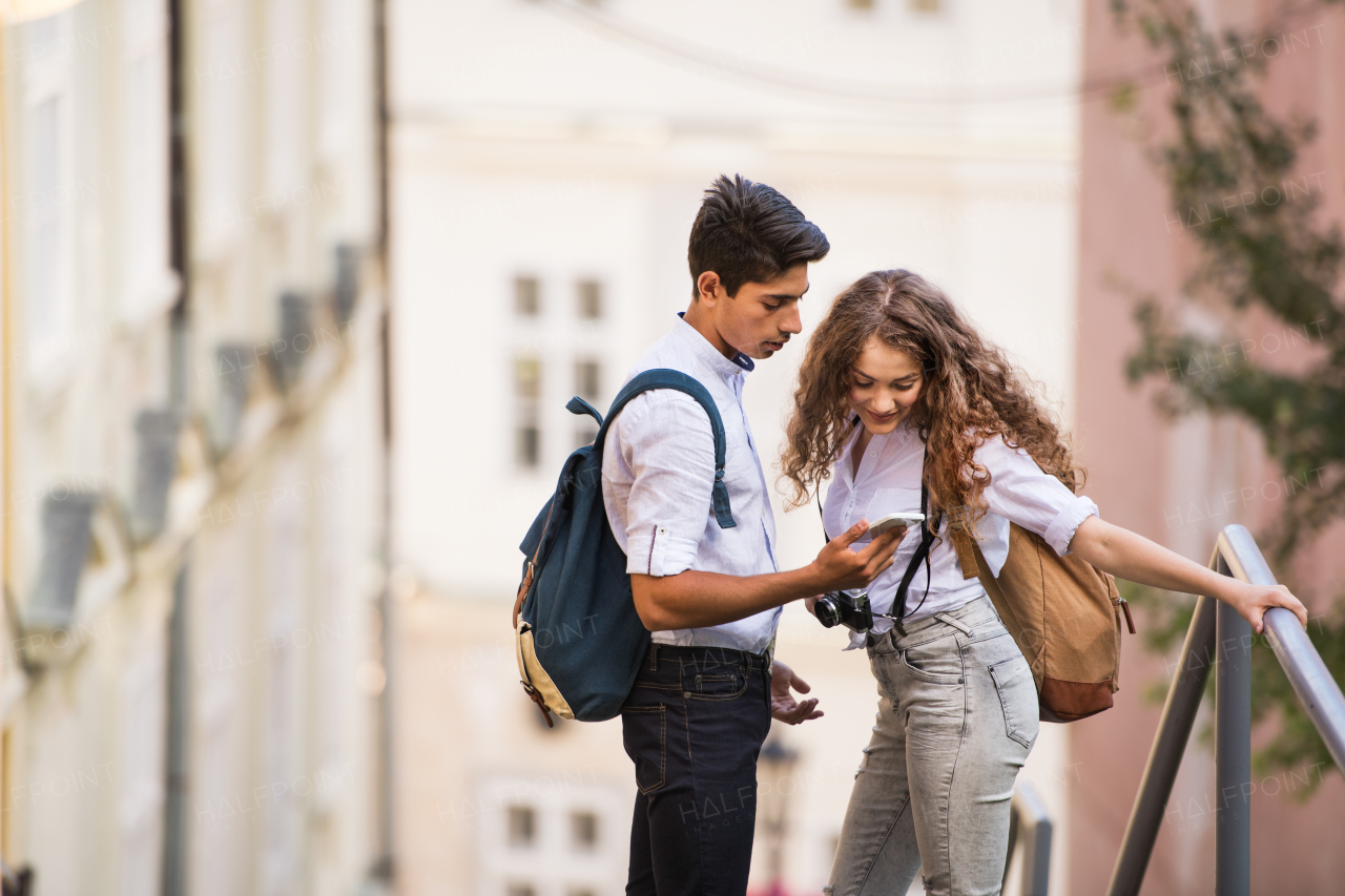 Two beautiful young tourists with smartphone and camera in the old town