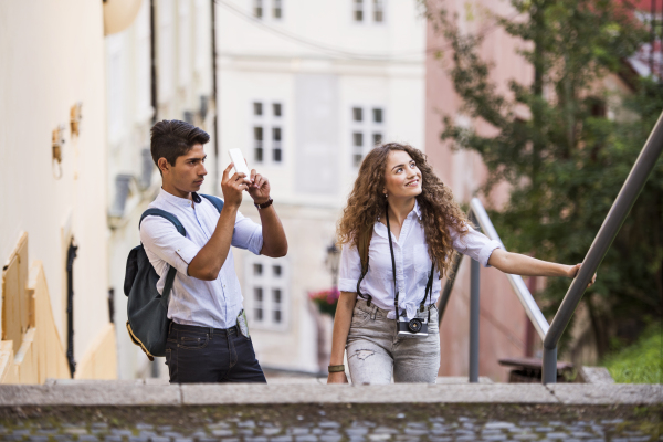 Two beautiful young tourists with smartphone and camera in the old town.