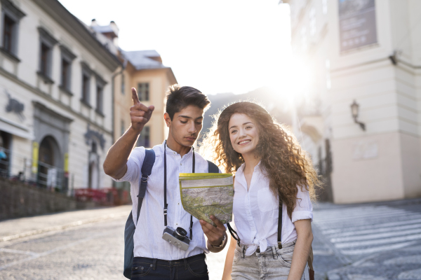 Two beautiful young tourists with map and camera in the old town.