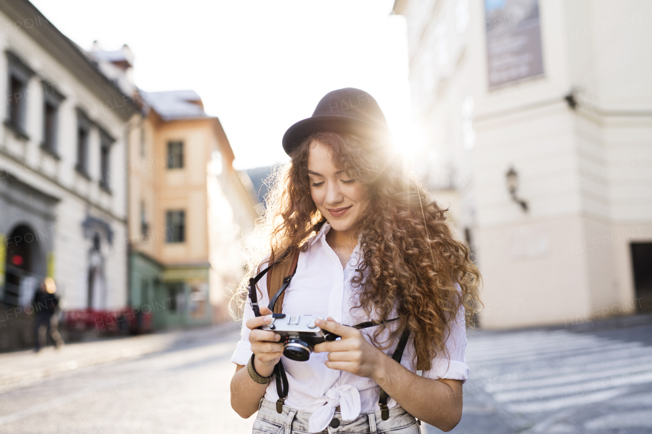 Beautiful young tourist with camera in the old town.