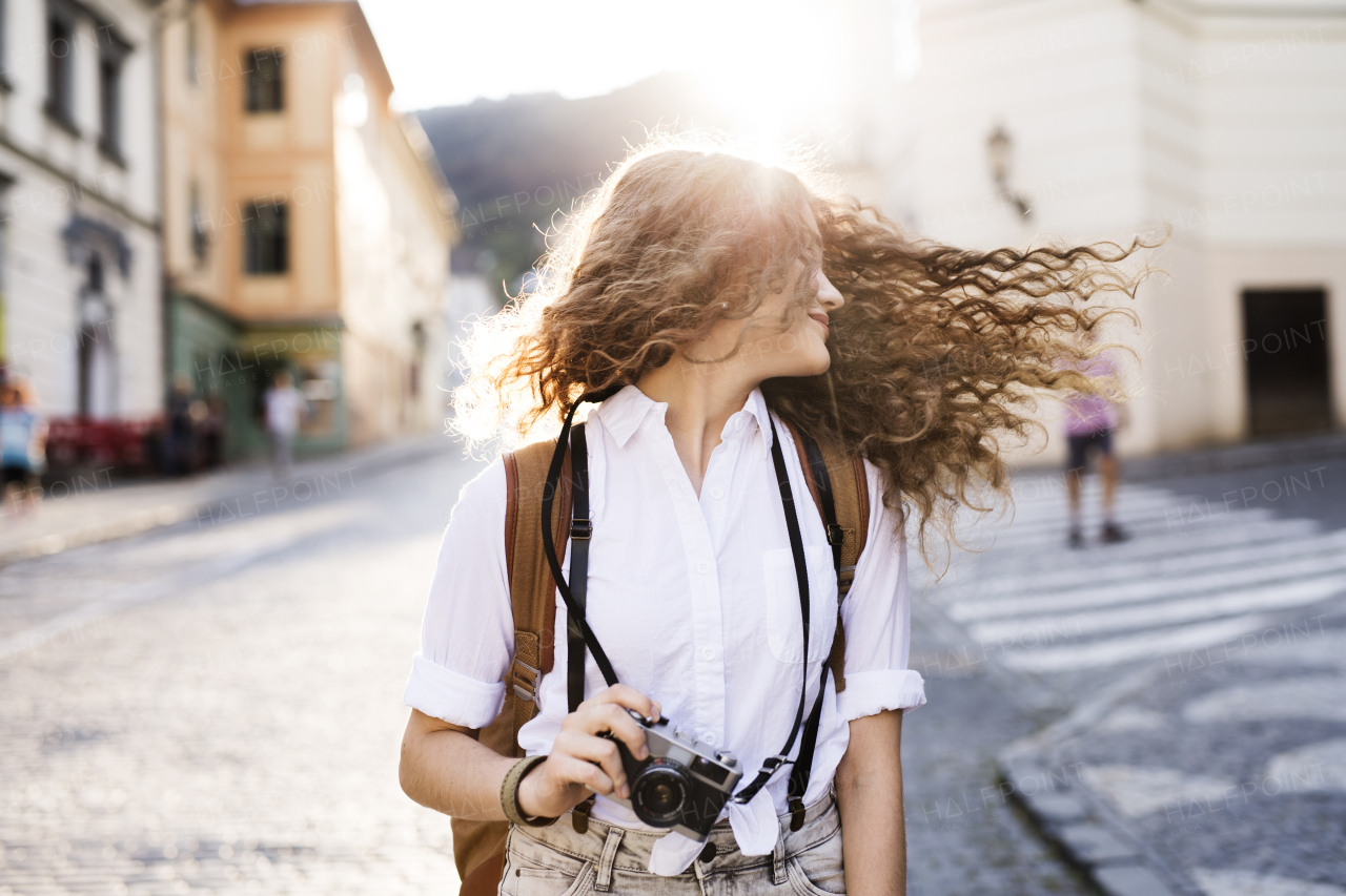 Beautiful young tourist with camera in the old town.