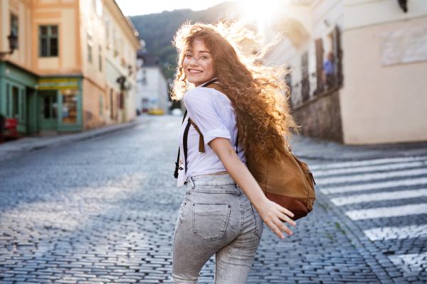 Beautiful young tourist with backpack and camera in the old town.