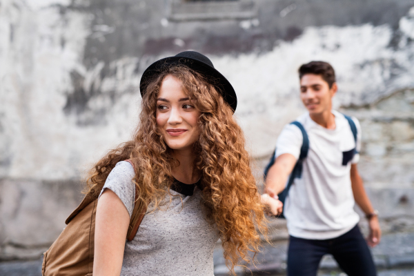 Two beautiful young tourists are in love in the old town, holding their hands.