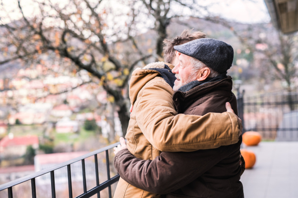 Senior father and his young son on a walk in town, hugging.