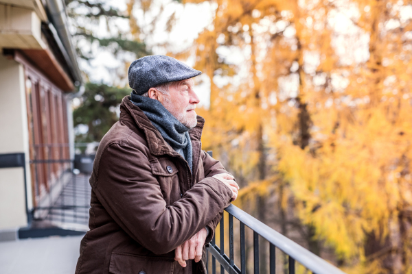 Senior man on a walk in town, standing on a terrace.