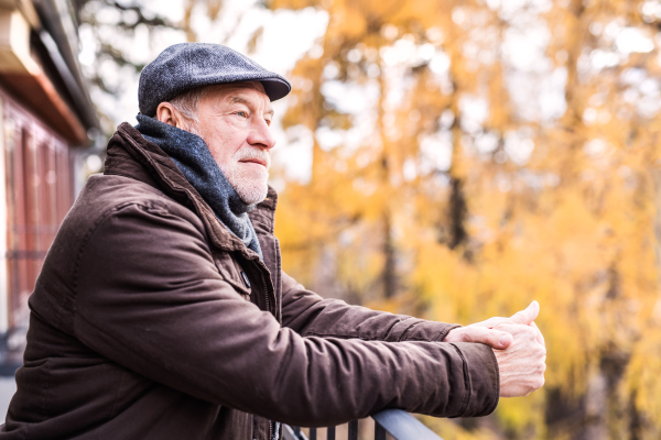 Happy senior man resting on a terrace in autumn nature.