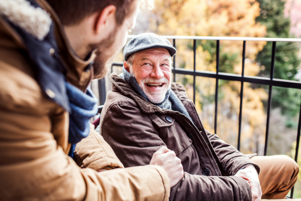 Father in wheelchair and young son on a walk. A carer assisting disabled senior man.