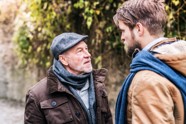 Senior father and his young son on a walk in town, talking.