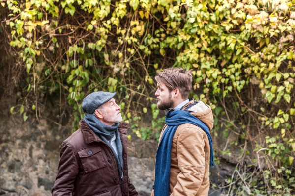 Senior father and his young son on a walk in town, talking.