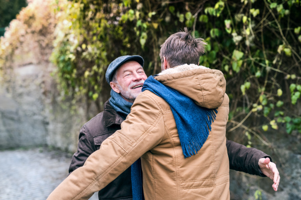 Senior father and his young son on a walk in town, hugging.