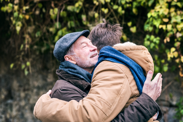 Senior father and his young son on a walk in town, hugging.