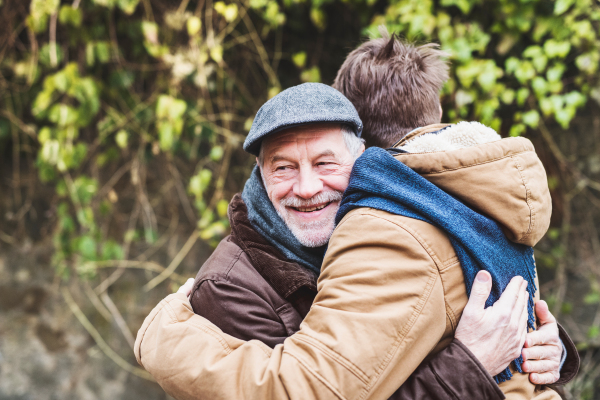 Senior father and his young son on a walk in town, hugging.