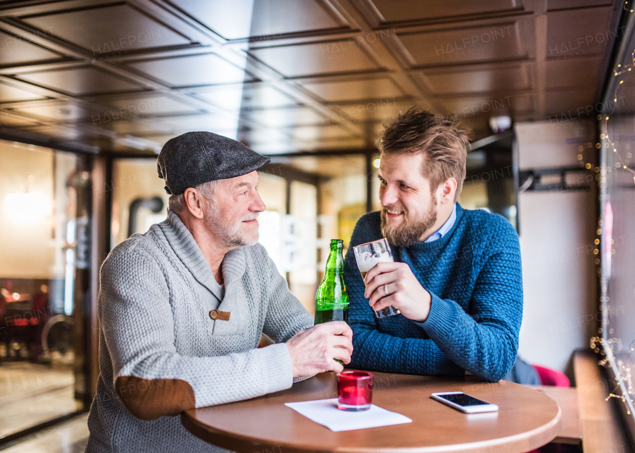 Senior father and his young son drinking beer in a pub.