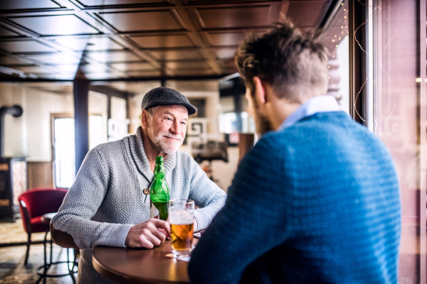 Senior father and his young son drinking beer in a pub.