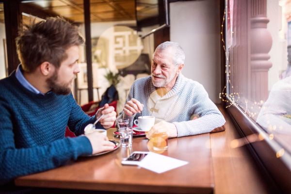 Senior father and his young son drinking coffee in a cafe.