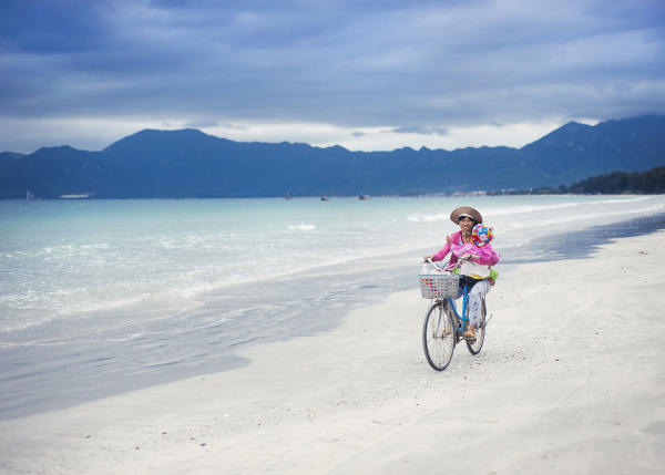 Vietnamese woman on a bicycle carrying her baby