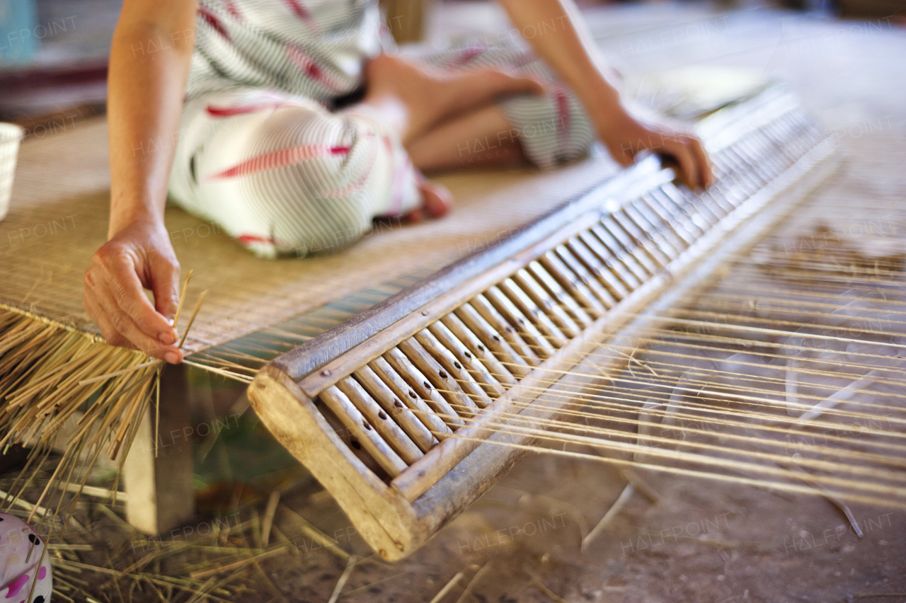 Unrecognizable vietnamese woman weaving a bamboo mat