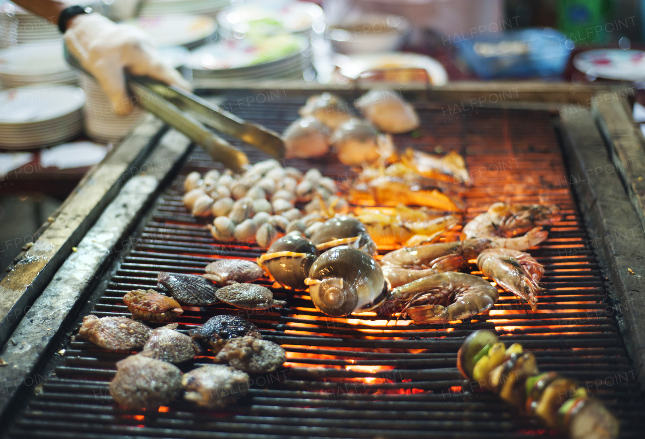 Unidentified man selling traditional asian style spicy grilled seafood at street market