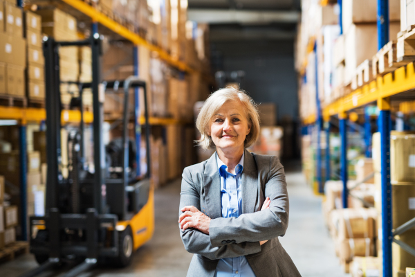 Portrait of a senior woman warehouse manager or supervisor, arms crossed.