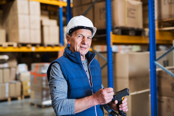 Portrait of a senior male warehouse worker or a supervisor with handheld barcode scanner.