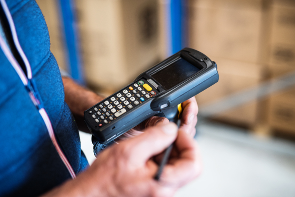 Unrecognizable male warehouse worker with barcode scanner. Close up.