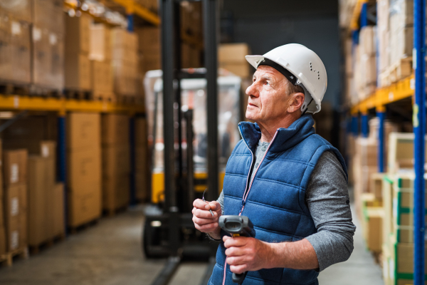 Portrait of a senior male warehouse worker or a supervisor with handheld barcode scanner.