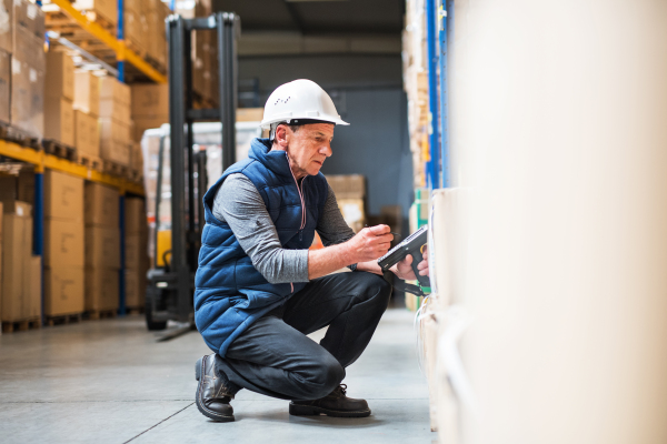 Portrait of a senior male warehouse worker or a supervisor with handheld barcode scanner.