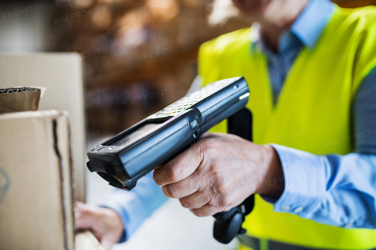 Unrecognizable warehouse woman worker or supervisor using a mobile handheld PC with barcode scanner.