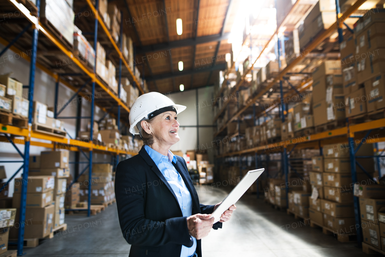 An attractive senior woman warehouse manager or supervisor working with tablet.