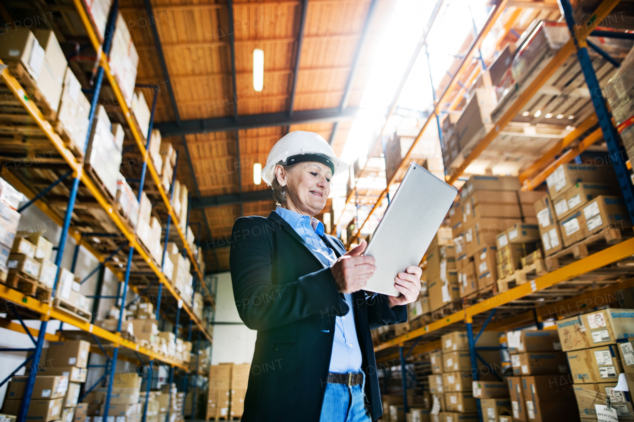 An attractive senior woman warehouse manager or supervisor working with tablet.