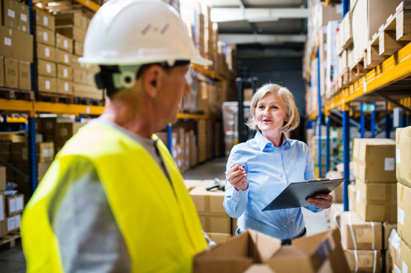 Senior woman manager and a man worker working together in a warehouse.