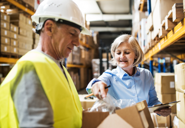 Senior woman manager and a man worker working together in a warehouse.