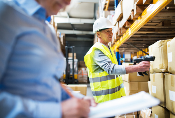 Unrecognizable senior woman manager and a man worker with barcode scanner working together in a warehouse.