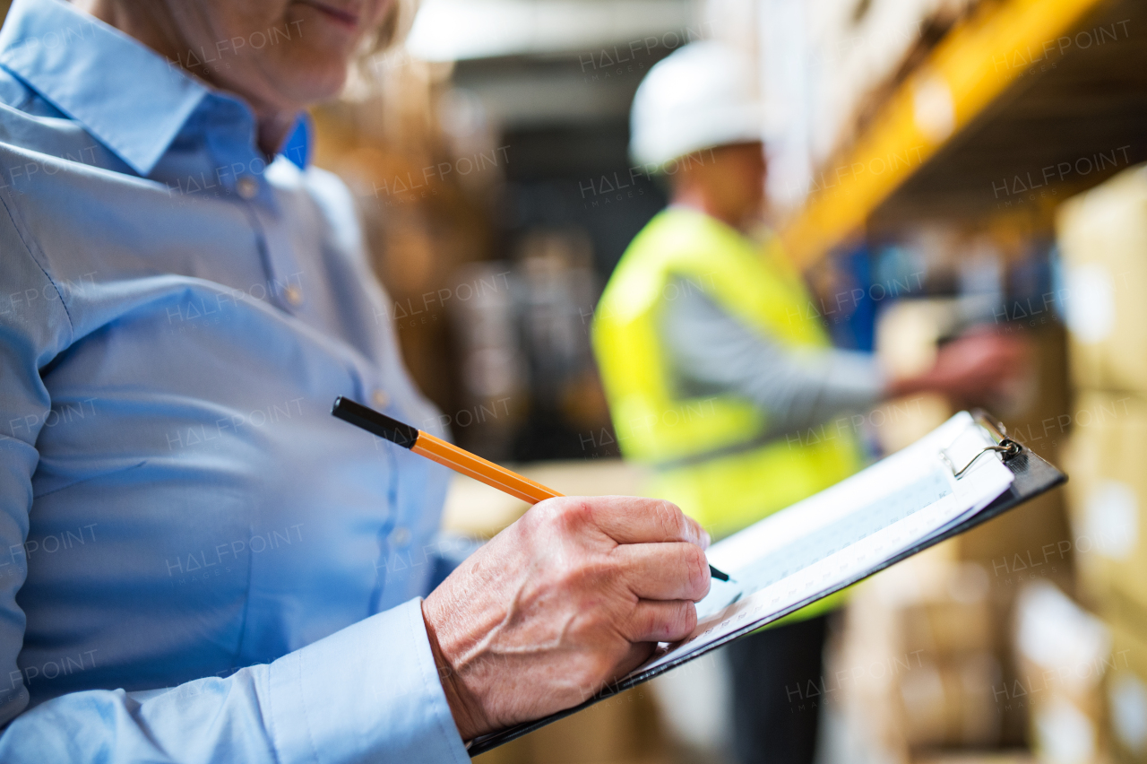 Unrecognizable senior woman manager and a man worker working together in a warehouse.