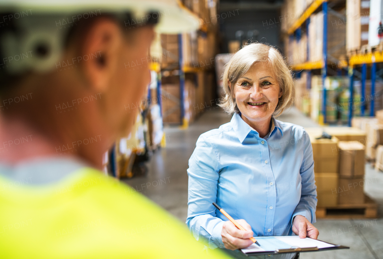 Senior woman manager and a man worker working together in a warehouse.