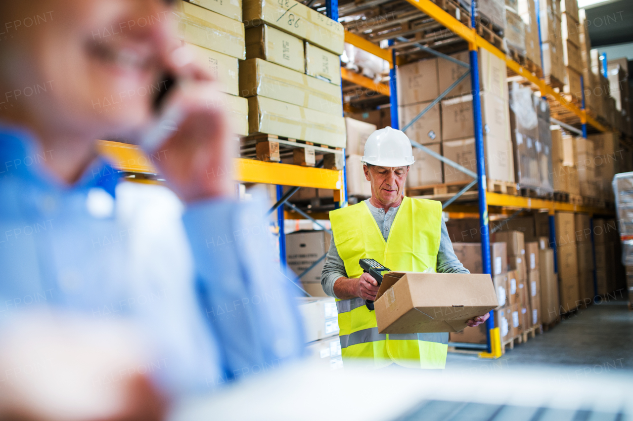 Unrecognizable senior woman manager with smartphone and man worker with barcode scanner working in a warehouse.