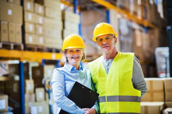 Portrait of a senior woman manager and a man worker standing together in a warehouse.