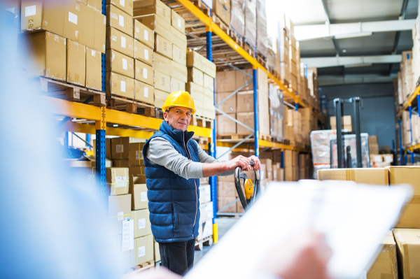 Unrecognizable senior woman manager and a man worker working together in a warehouse.