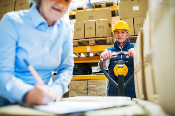 Senior woman manager and a man worker working together in a warehouse.