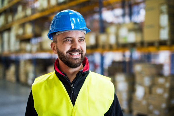 Portrait of a male warehouse worker with blue helmet.